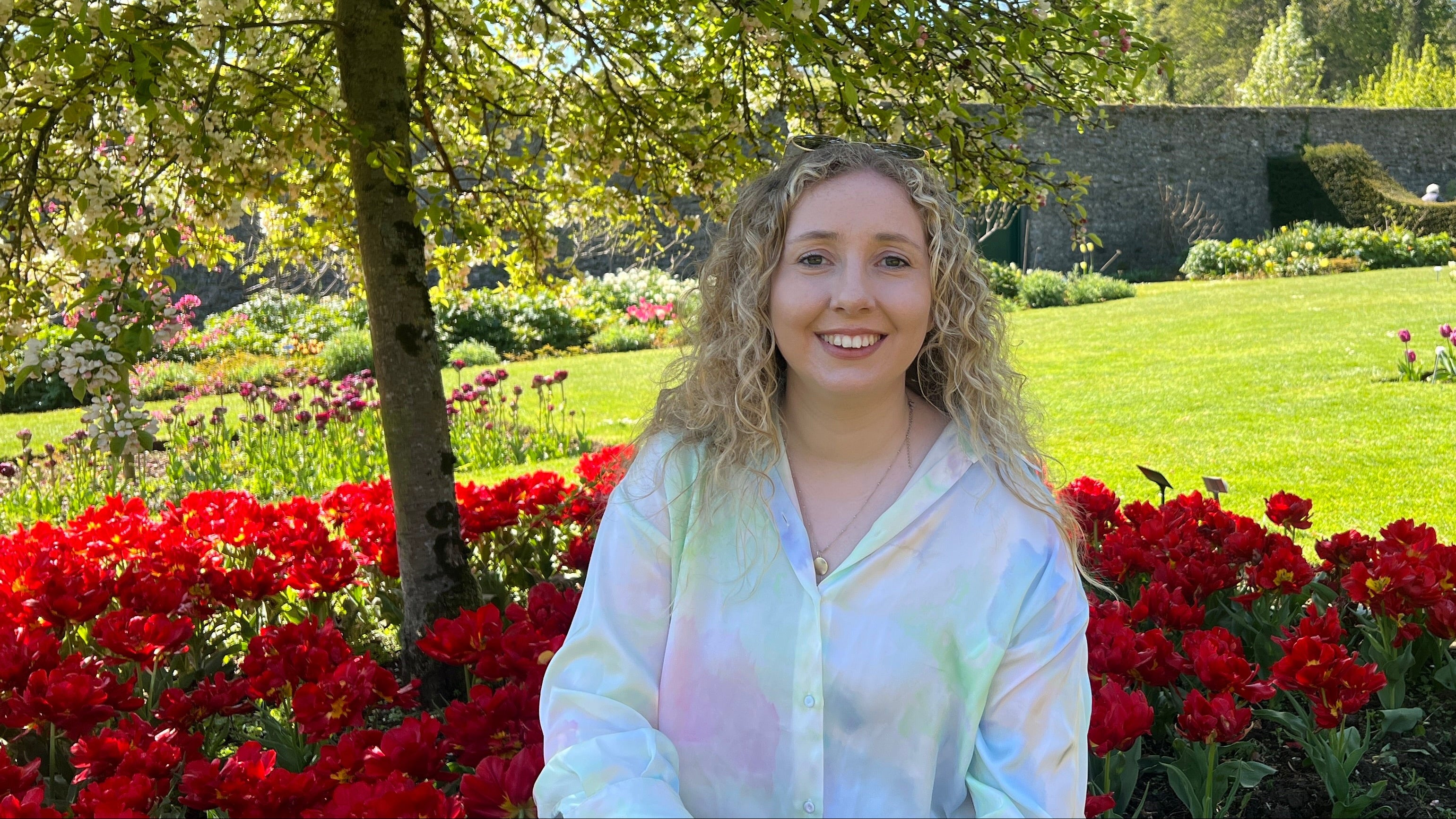 Joanna Melanie in a garden with red flowers and greenery